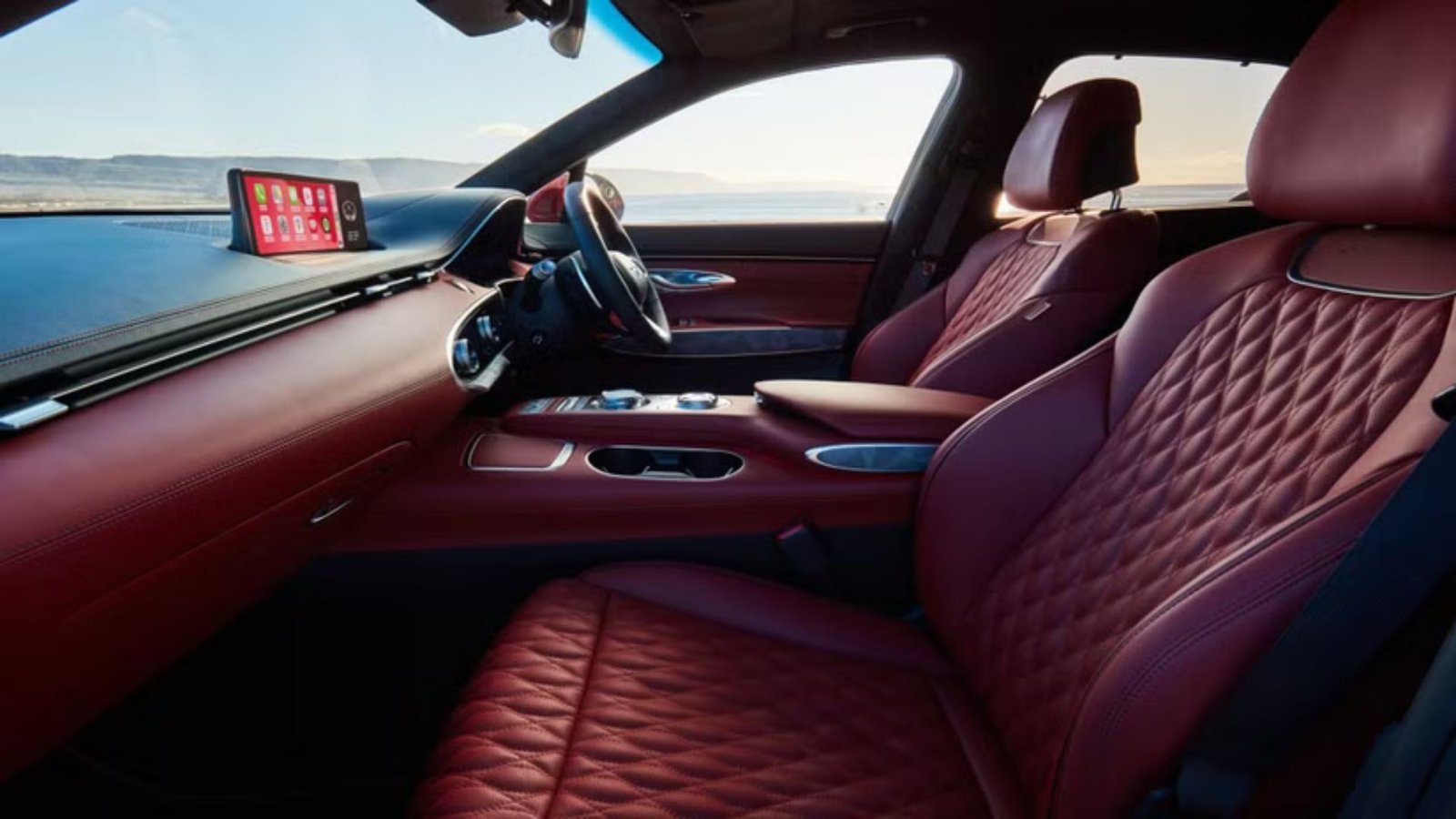 Close-up shot of the front seats in a Genesis GV70, finished in a dark red leather.