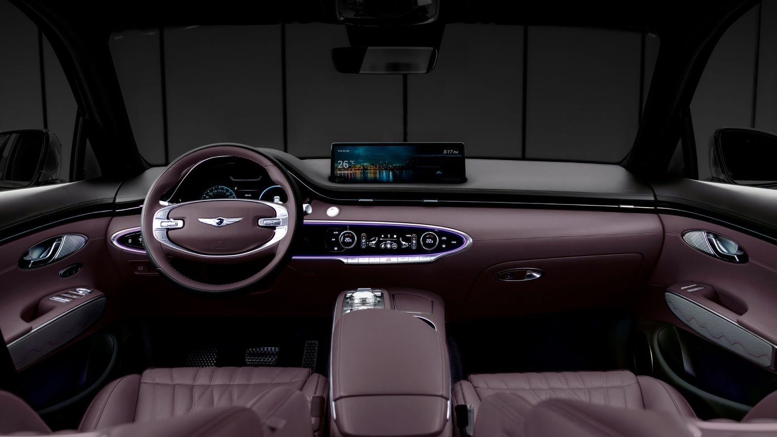 Shot inside the cabin of a Genesis GV70, showing the front seats, center console, steering wheel, and infotainment screen.