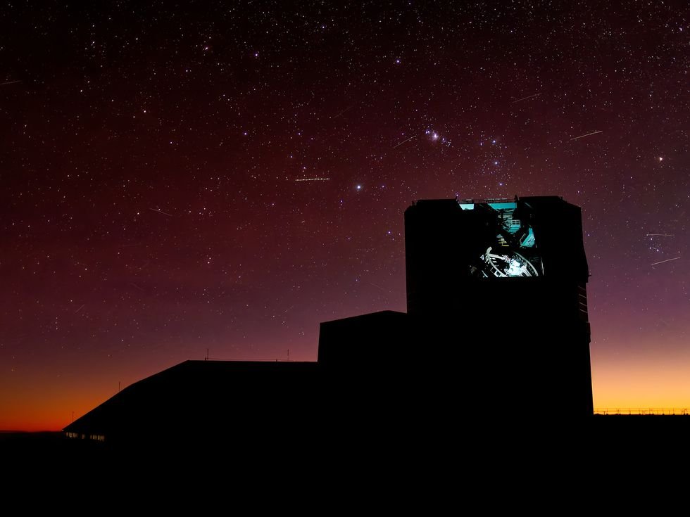 Silhouetted telescope under a starry sky and vibrant, colorful sunset.