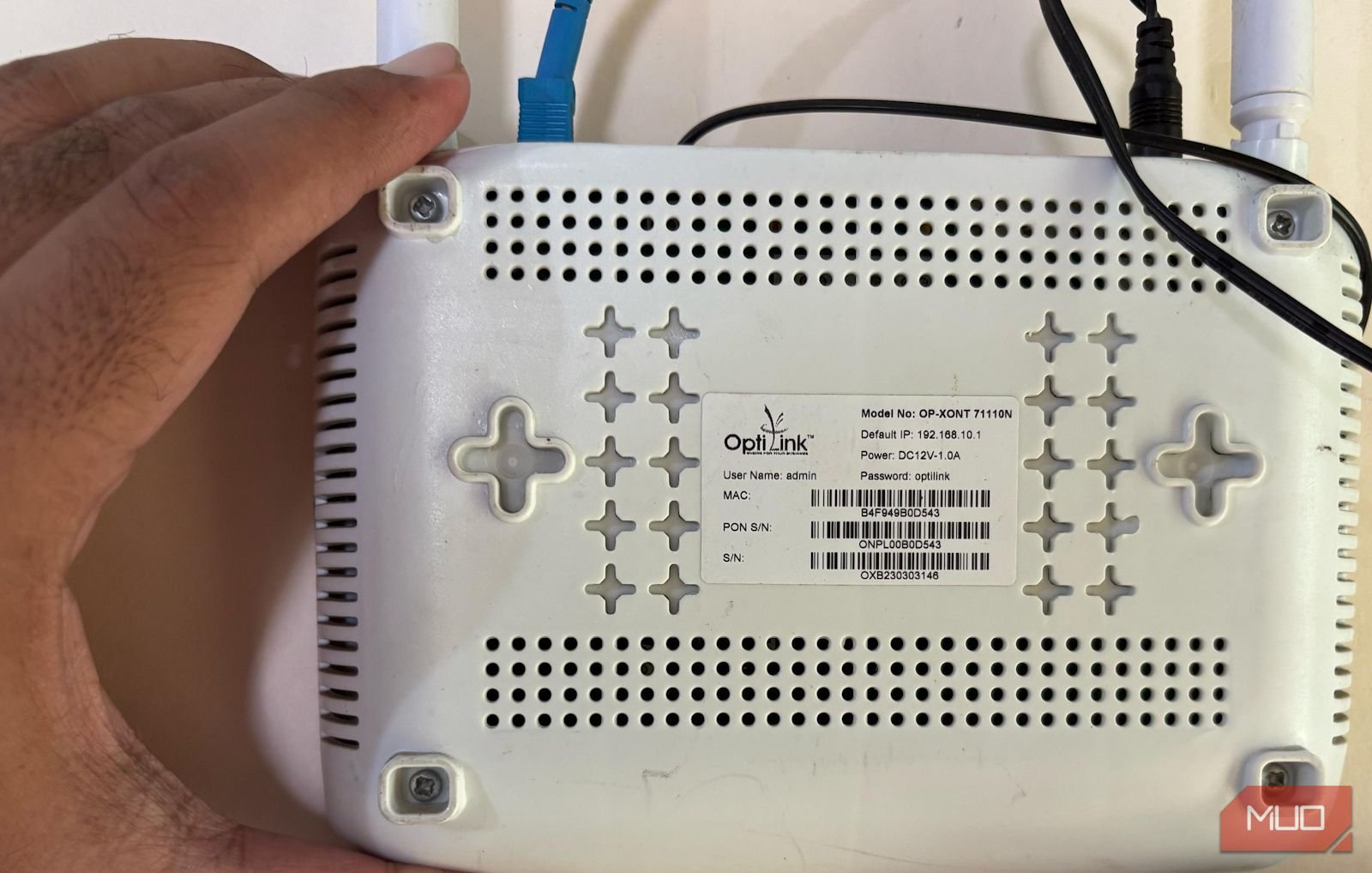 A hand holds a router and shows its back