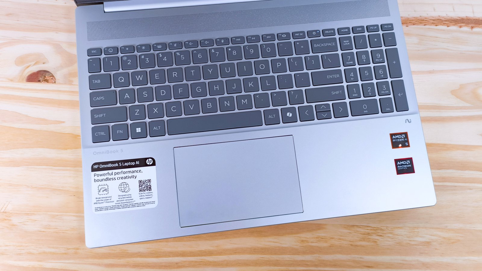 The keyboard deck of the HP Omnibook 5 Laptop AI on a wood table