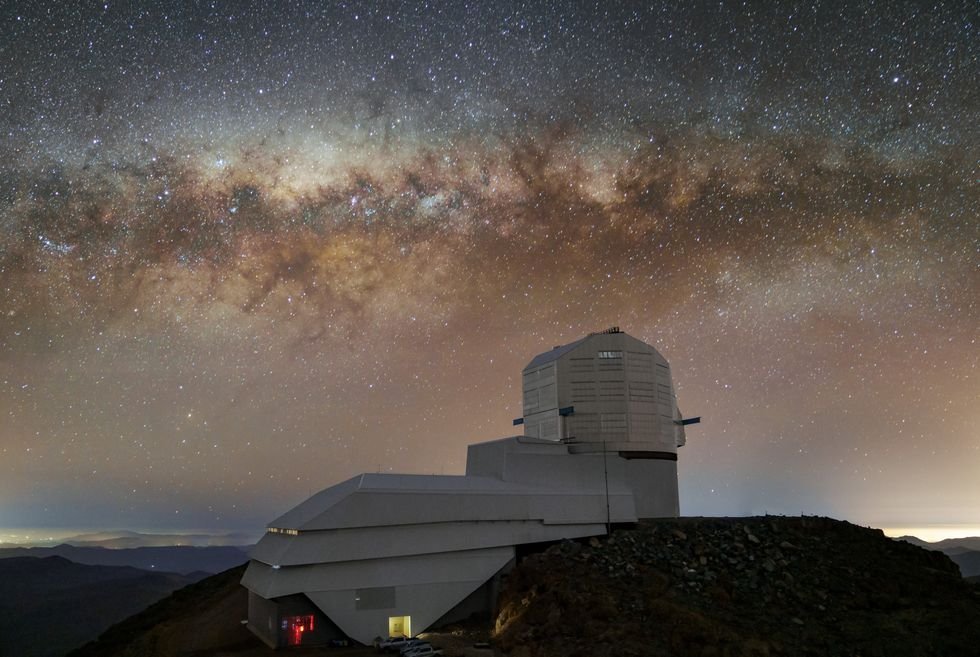 Observatory under Milky Way band at twilight, stars densely scatter across the clear sky.